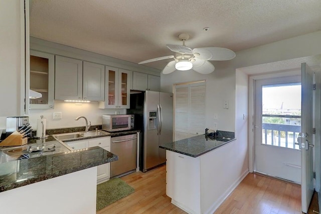 kitchen with appliances with stainless steel finishes, light hardwood / wood-style flooring, sink, and kitchen peninsula