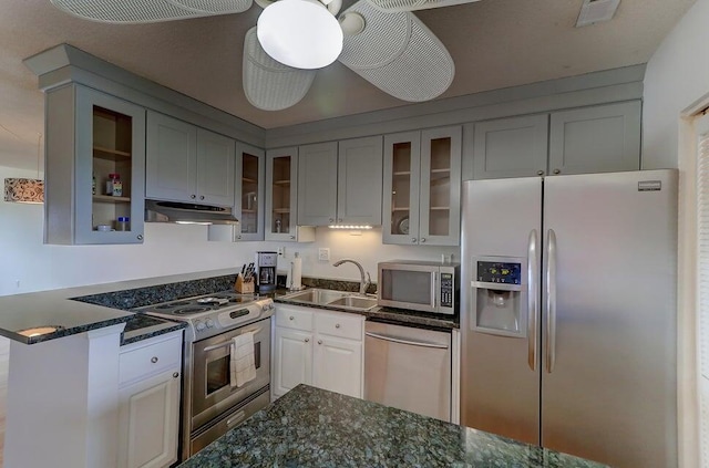 kitchen featuring appliances with stainless steel finishes, ceiling fan, sink, white cabinetry, and dark stone countertops