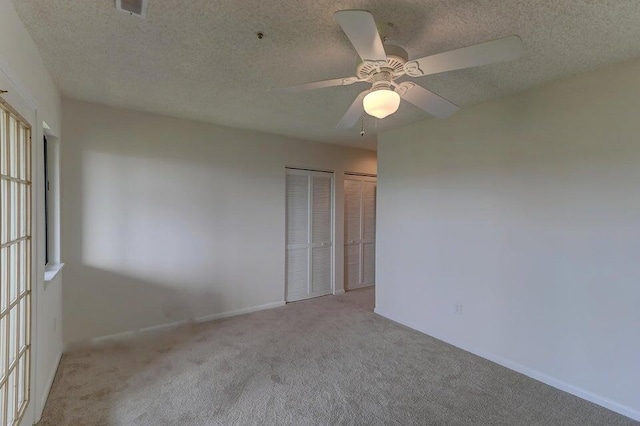 carpeted spare room with a textured ceiling and ceiling fan