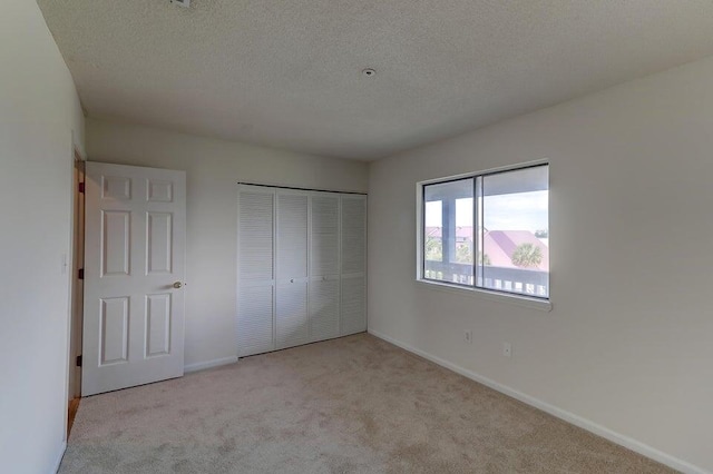 unfurnished bedroom with light carpet, a closet, and a textured ceiling