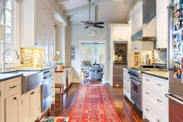 kitchen with high quality appliances, white cabinetry, tasteful backsplash, sink, and vaulted ceiling with beams