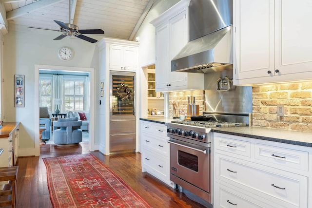 kitchen featuring dark wood-type flooring, white cabinetry, lofted ceiling with beams, premium appliances, and wall chimney range hood