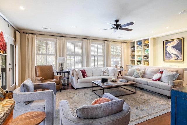 living room featuring ceiling fan, hardwood / wood-style flooring, and built in shelves