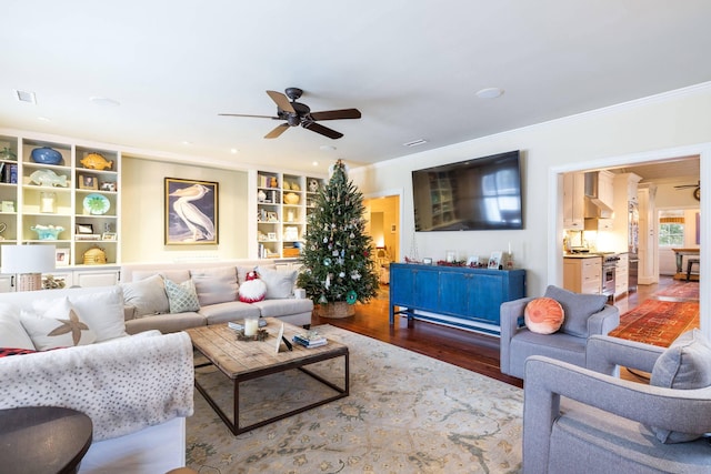 living room with crown molding, ceiling fan, dark hardwood / wood-style flooring, and built in features