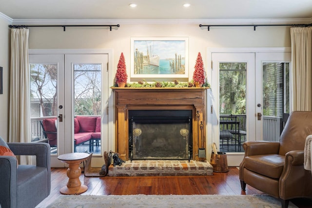 sitting room with wood-type flooring, ornamental molding, a fireplace, and french doors