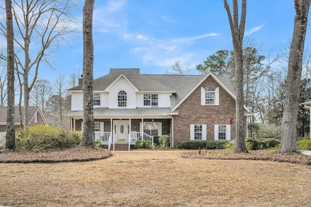 view of front of property with a shingled roof, covered porch, and brick siding