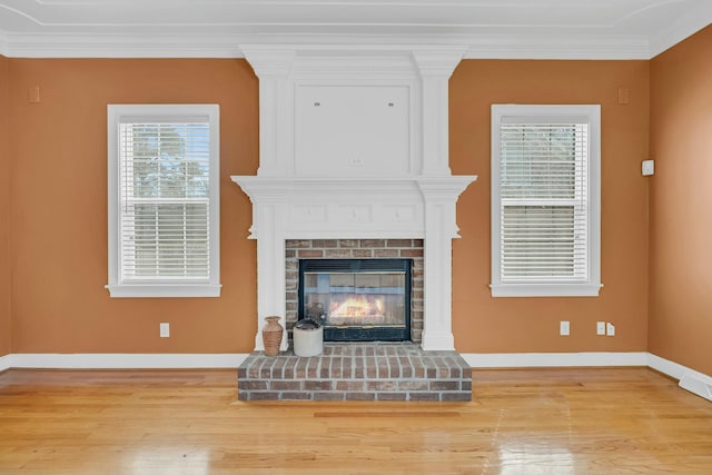 living room featuring ornamental molding, a brick fireplace, baseboards, and wood finished floors