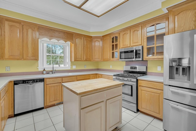 kitchen featuring appliances with stainless steel finishes, light tile patterned floors, a sink, and wooden counters