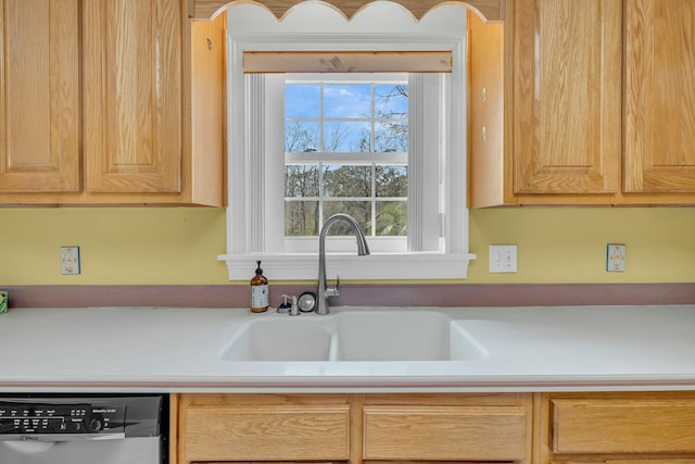 kitchen with light countertops, light brown cabinets, dishwasher, and a sink