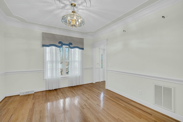 unfurnished dining area featuring crown molding, visible vents, a notable chandelier, and wood finished floors