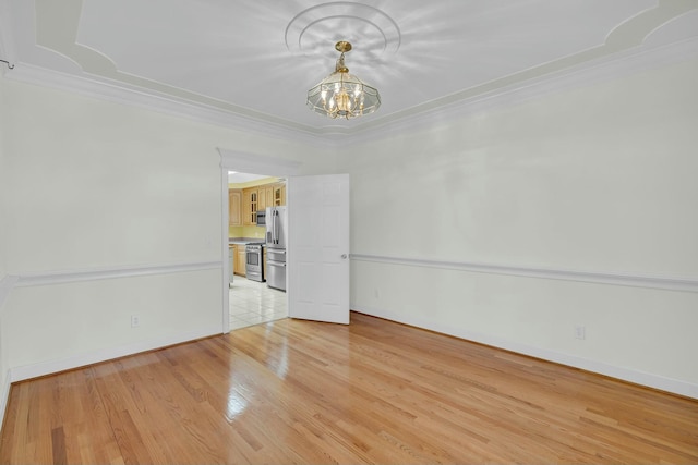 unfurnished room with an inviting chandelier, baseboards, ornamental molding, and light wood-style floors