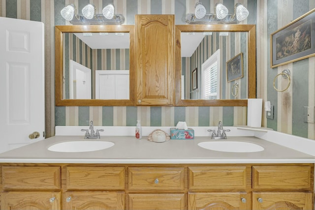 full bathroom featuring double vanity, a sink, and wallpapered walls