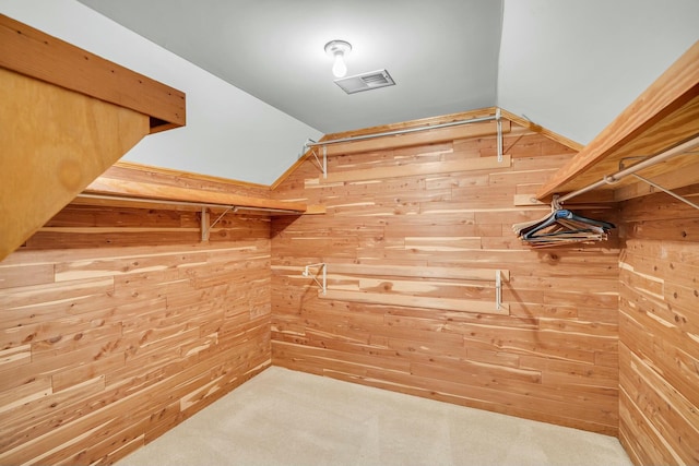 spacious closet with lofted ceiling, carpet flooring, and visible vents