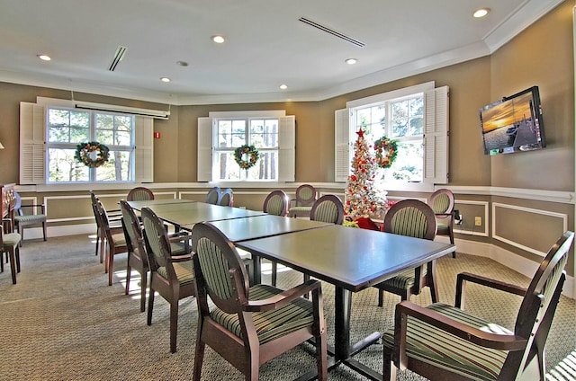 dining room with carpet floors, a wainscoted wall, crown molding, visible vents, and a decorative wall