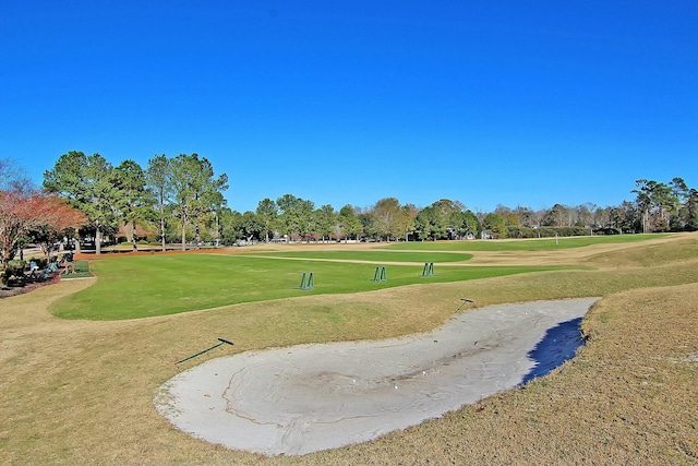 view of community featuring view of golf course and a yard