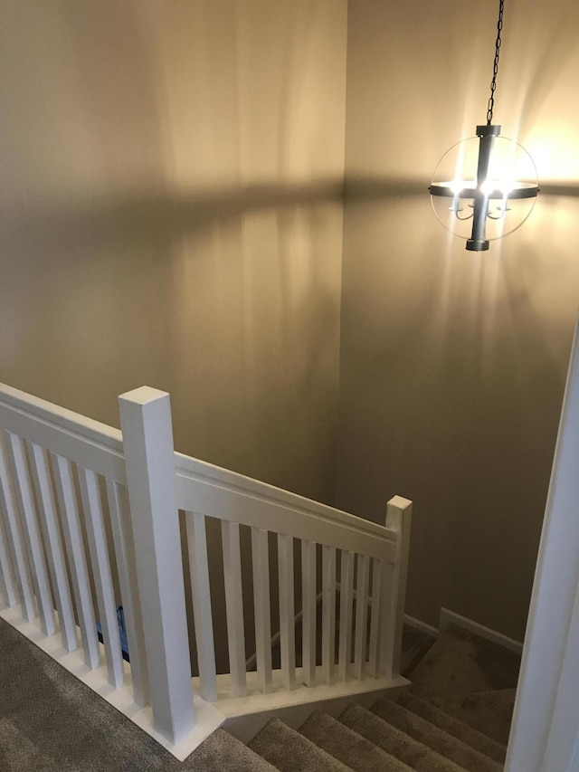 stairway featuring a chandelier and carpet