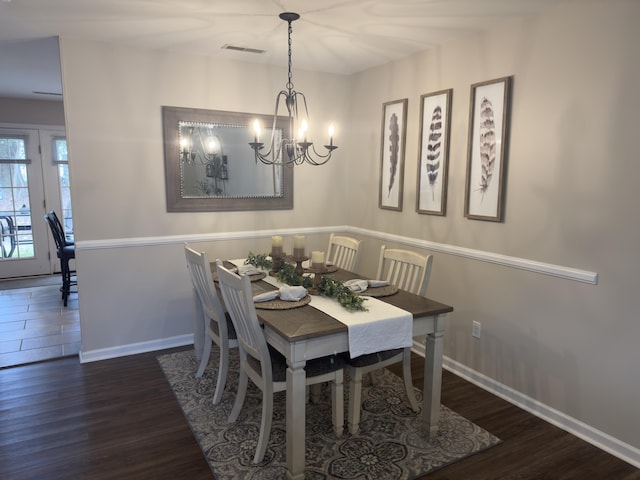 dining space with visible vents, a notable chandelier, baseboards, and wood finished floors