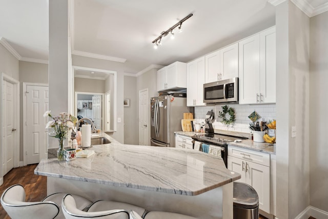 kitchen with stainless steel appliances, light stone countertops, a breakfast bar, and a sink