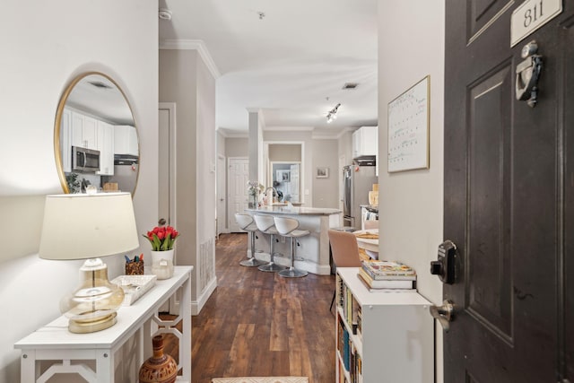 entryway featuring dark wood finished floors, ornamental molding, and visible vents