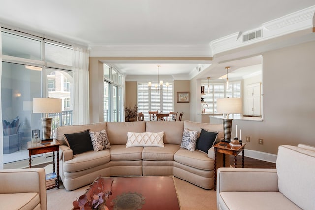 living area featuring crown molding, a chandelier, baseboards, and wood finished floors