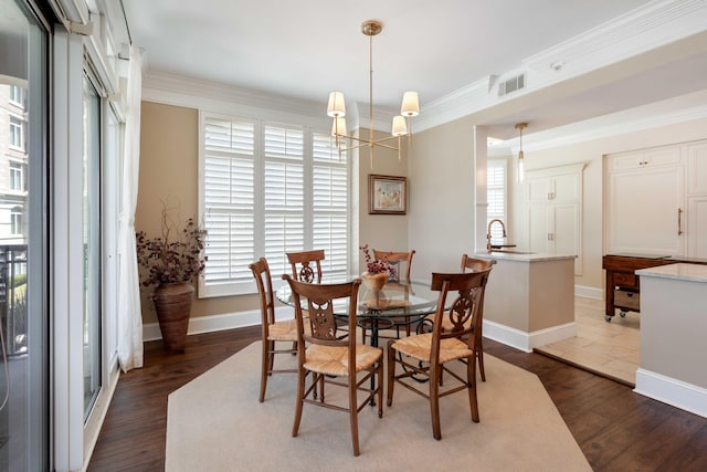dining area with dark wood-style flooring, a chandelier, baseboards, and ornamental molding