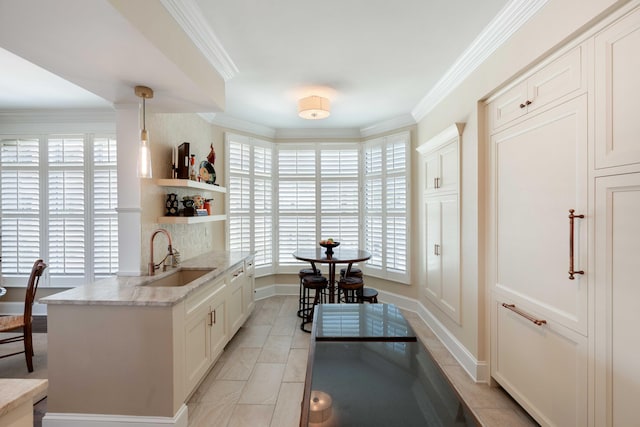 kitchen with a sink, crown molding, open shelves, light stone counters, and white cabinetry