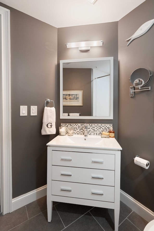 bathroom featuring tile patterned flooring, vanity, baseboards, and decorative backsplash