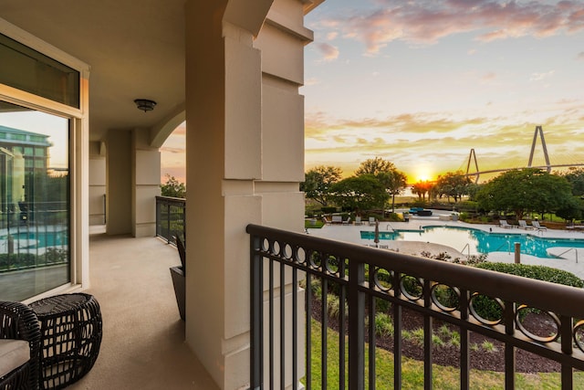 balcony at dusk with view of pool