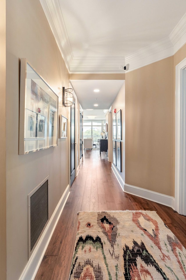 corridor featuring ornamental molding, wood-type flooring, and baseboards