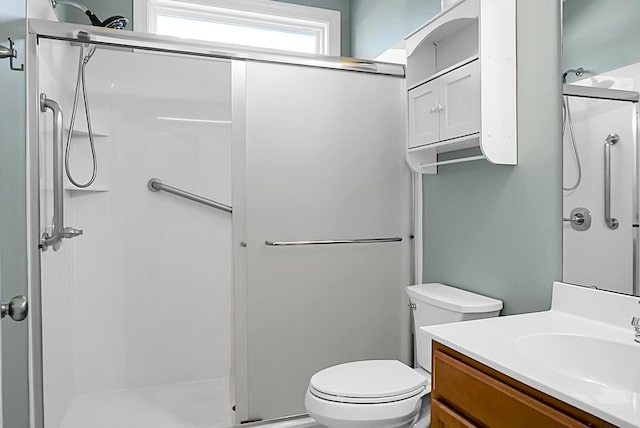 bathroom with vanity, toilet, and a shower with door