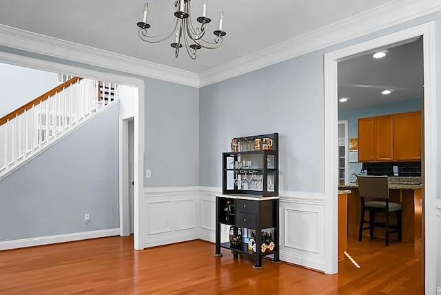 dining room with light hardwood / wood-style floors, crown molding, and an inviting chandelier