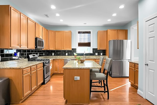 kitchen featuring a kitchen breakfast bar, a kitchen island, stainless steel appliances, and light hardwood / wood-style flooring