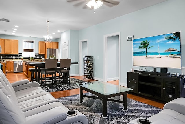 living room with ceiling fan with notable chandelier, light hardwood / wood-style flooring, and sink