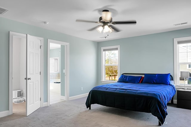 carpeted bedroom with ensuite bath and ceiling fan