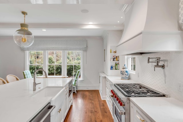 kitchen with high end stainless steel range oven, custom exhaust hood, white cabinets, and decorative light fixtures