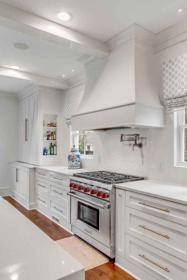 kitchen with custom exhaust hood, luxury range, light countertops, white cabinetry, and open shelves