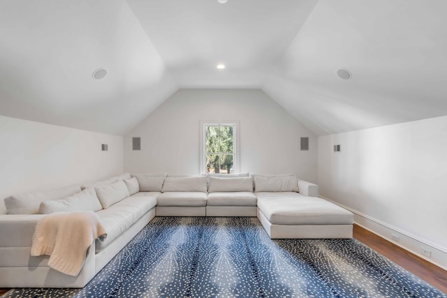 living room featuring lofted ceiling, visible vents, baseboards, and wood finished floors