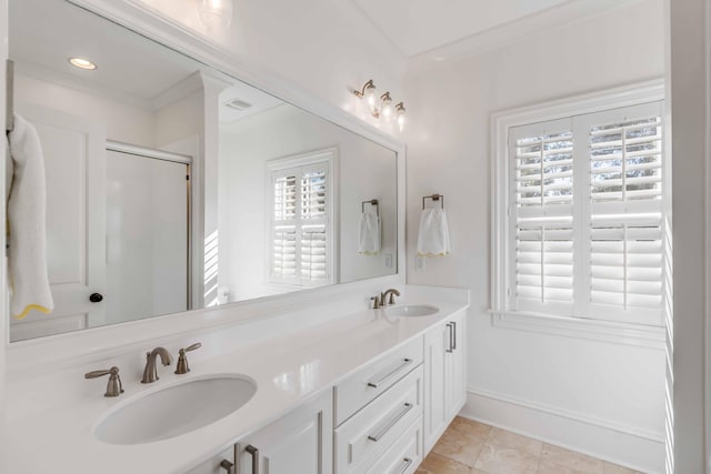 bathroom featuring double vanity, a shower stall, ornamental molding, and a sink