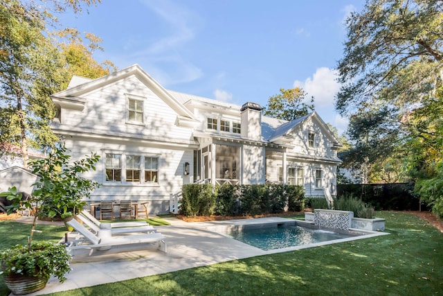 rear view of property with a yard, an outdoor pool, a patio, and a chimney