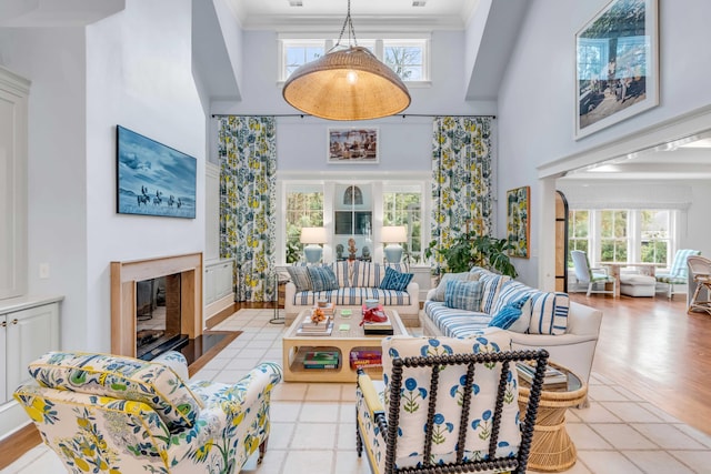 living room featuring ornamental molding, a towering ceiling, and a fireplace with flush hearth