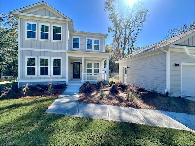 view of front of house featuring a garage, a front yard, and covered porch