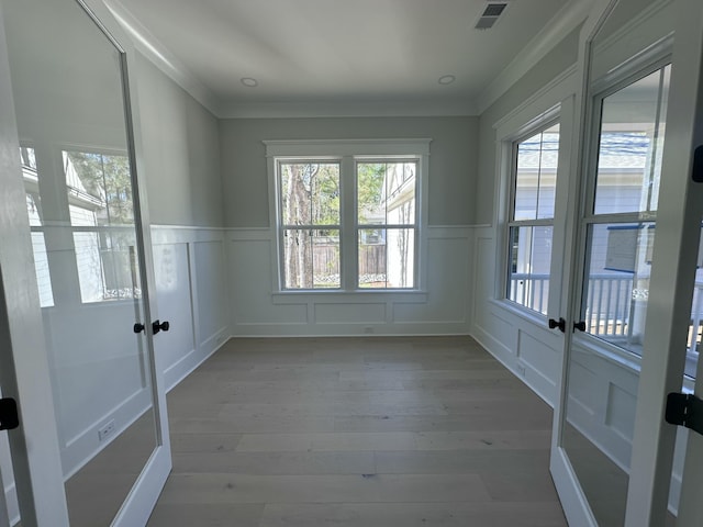 empty room with ornamental molding and light wood-type flooring