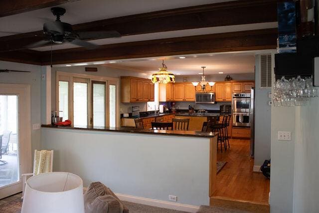 1866 Capri Dr, Charleston, SC 29407 - kitchen with stainless steel appliances, dark countertops, a ceiling fan, a peninsula, and a chandelier