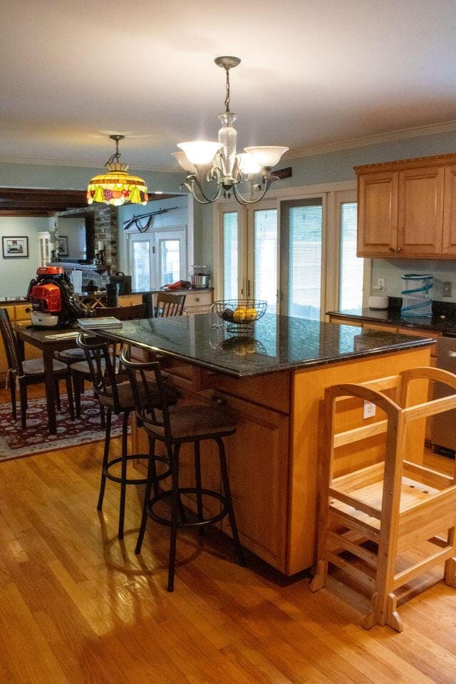 1866 Capri Dr, Charleston, SC 29407 - kitchen featuring ornamental molding, a chandelier, a kitchen bar, light wood finished floors, and brown cabinets