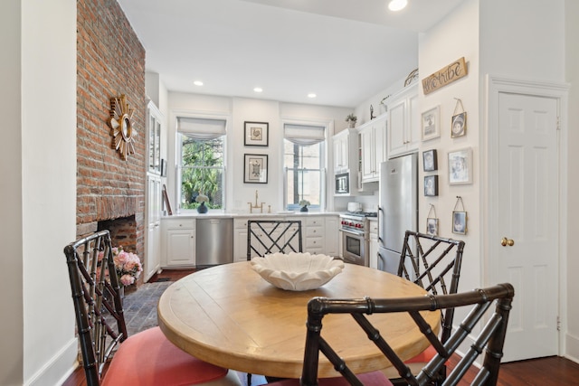 dining area featuring dark hardwood / wood-style flooring and a brick fireplace