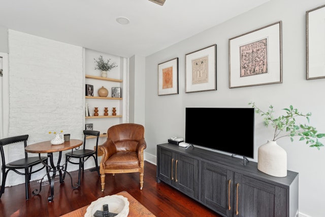 sitting room featuring built in shelves and dark wood-type flooring