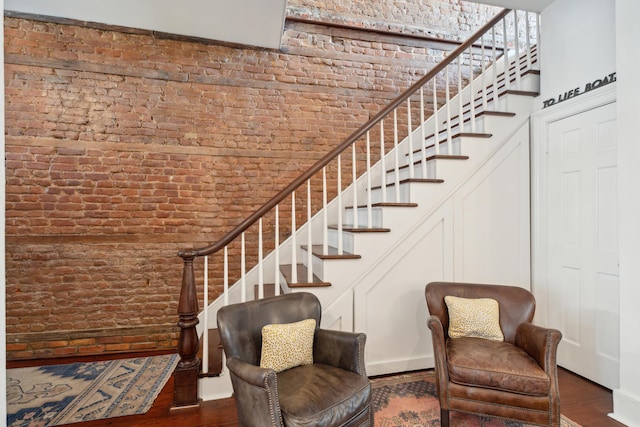 stairway with wood-type flooring and brick wall