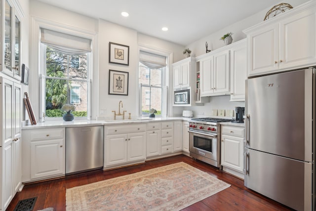 kitchen with dark hardwood / wood-style flooring, a wealth of natural light, stainless steel appliances, sink, and white cabinetry