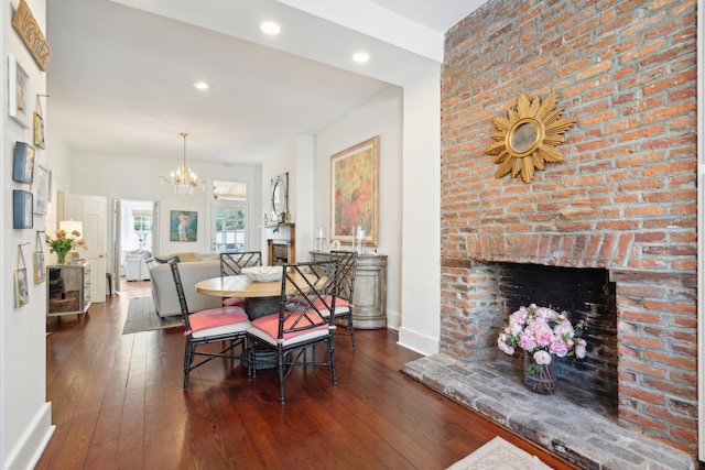 dining space featuring a notable chandelier, dark hardwood / wood-style flooring, and a fireplace