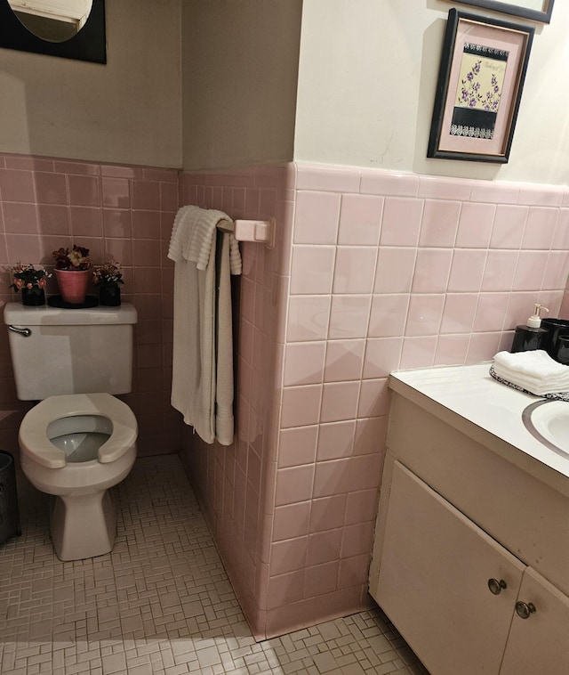 bathroom with tile patterned flooring, vanity, toilet, and tile walls